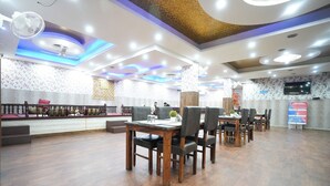 Un restaurante con mesas y sillas de madera, un muro con diseño y un techo con iluminación empotrada.