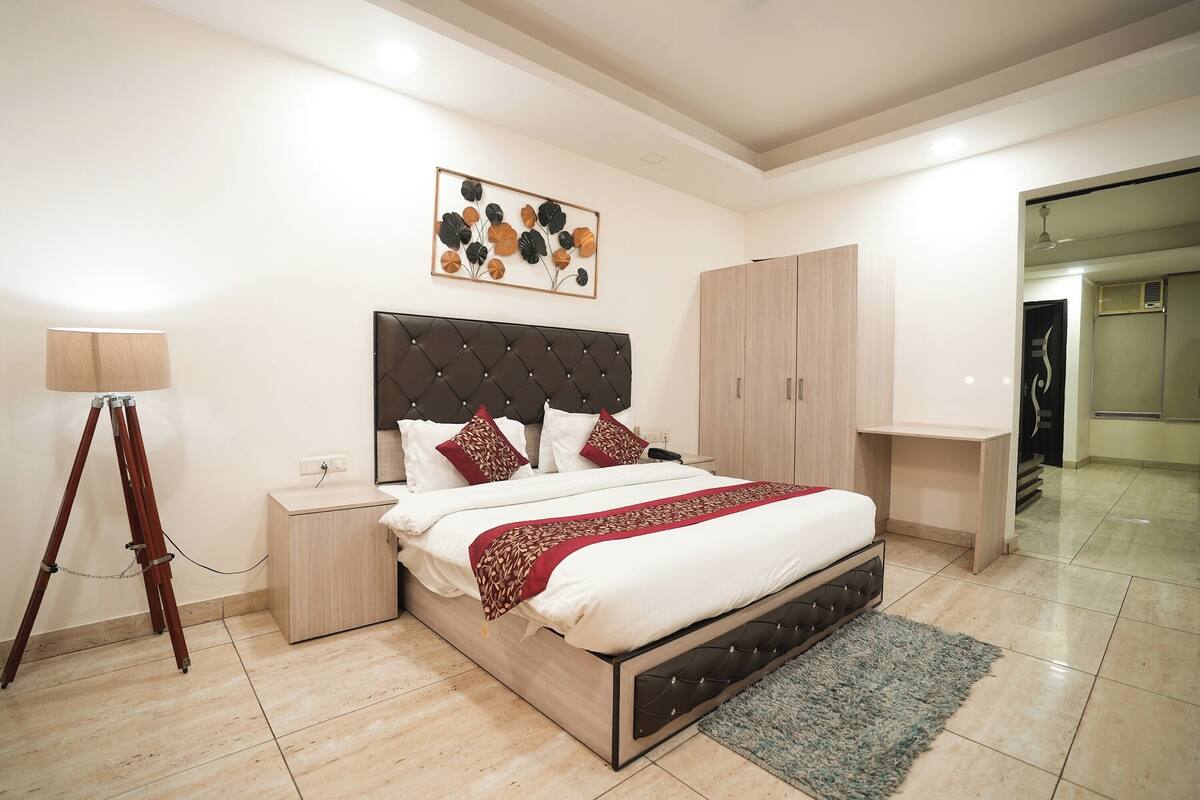A modern bedroom with a large bed, a bedside table, a lamp, and a wardrobe.