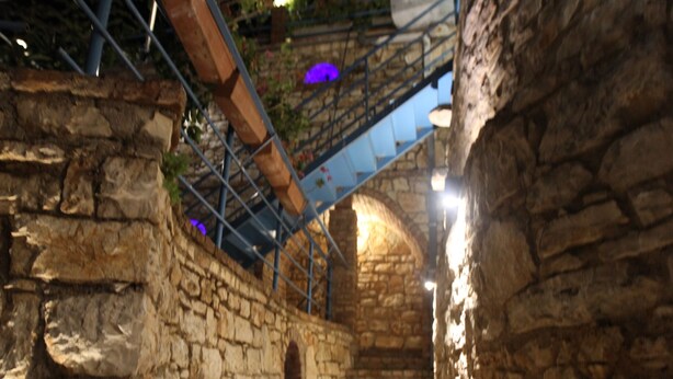 Eine Steintreppe führt nach oben, umgeben von Steinmauern und Metallgeländern.