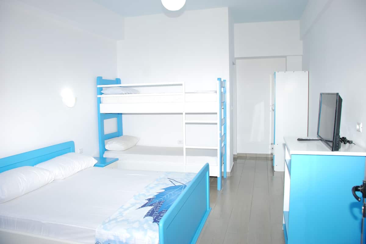 A room with bunk beds, a desk, a television, and a refrigerator.