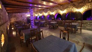 Ein Restaurant mit Steinwänden, Holzbalken und gedeckten Tischen.