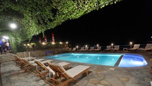 Ein Poolbereich mit Liegestühlen und Steinböden.