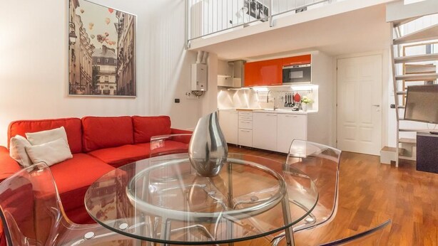 A modern living room with a red sofa, a glass coffee table, and a kitchen in the background. - Alessia's Flat - Portello 2 (Milan)