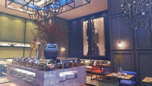 Un restaurante moderno con una zona de bufé central, disposición de mesas y elementos decorativos.