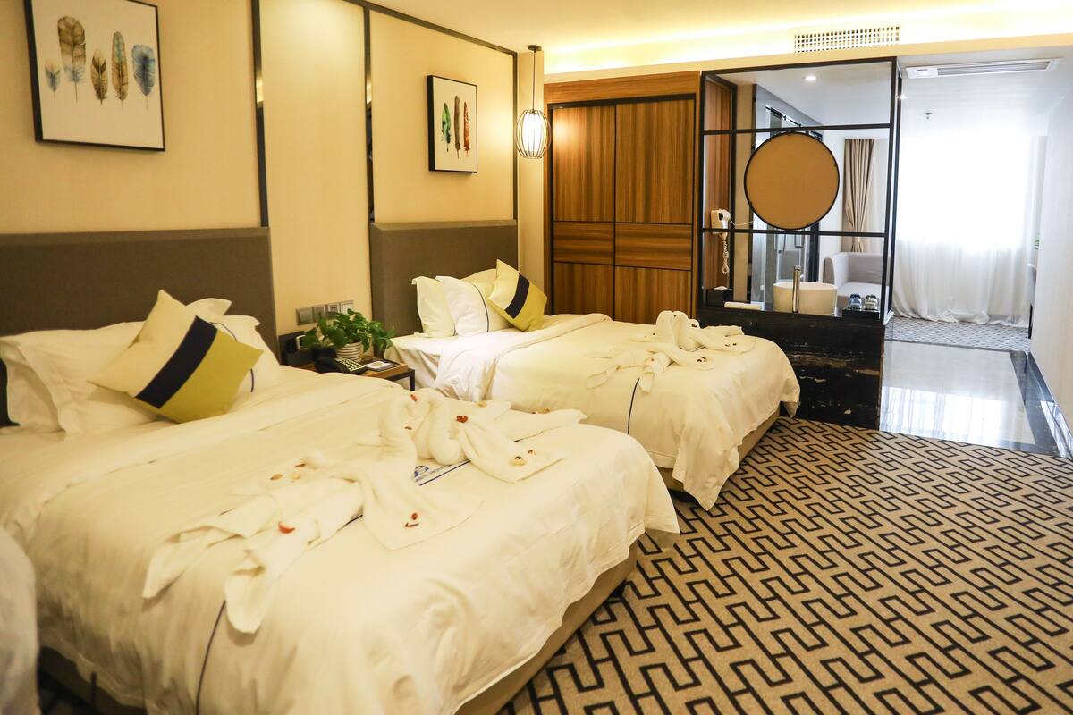 A hotel room with two beds, a large mirror, and a view of the city.