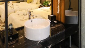 Un baño moderno con un espejo redondo, un lavabo blanco, un secador de pelo y un perchero para toallas.
