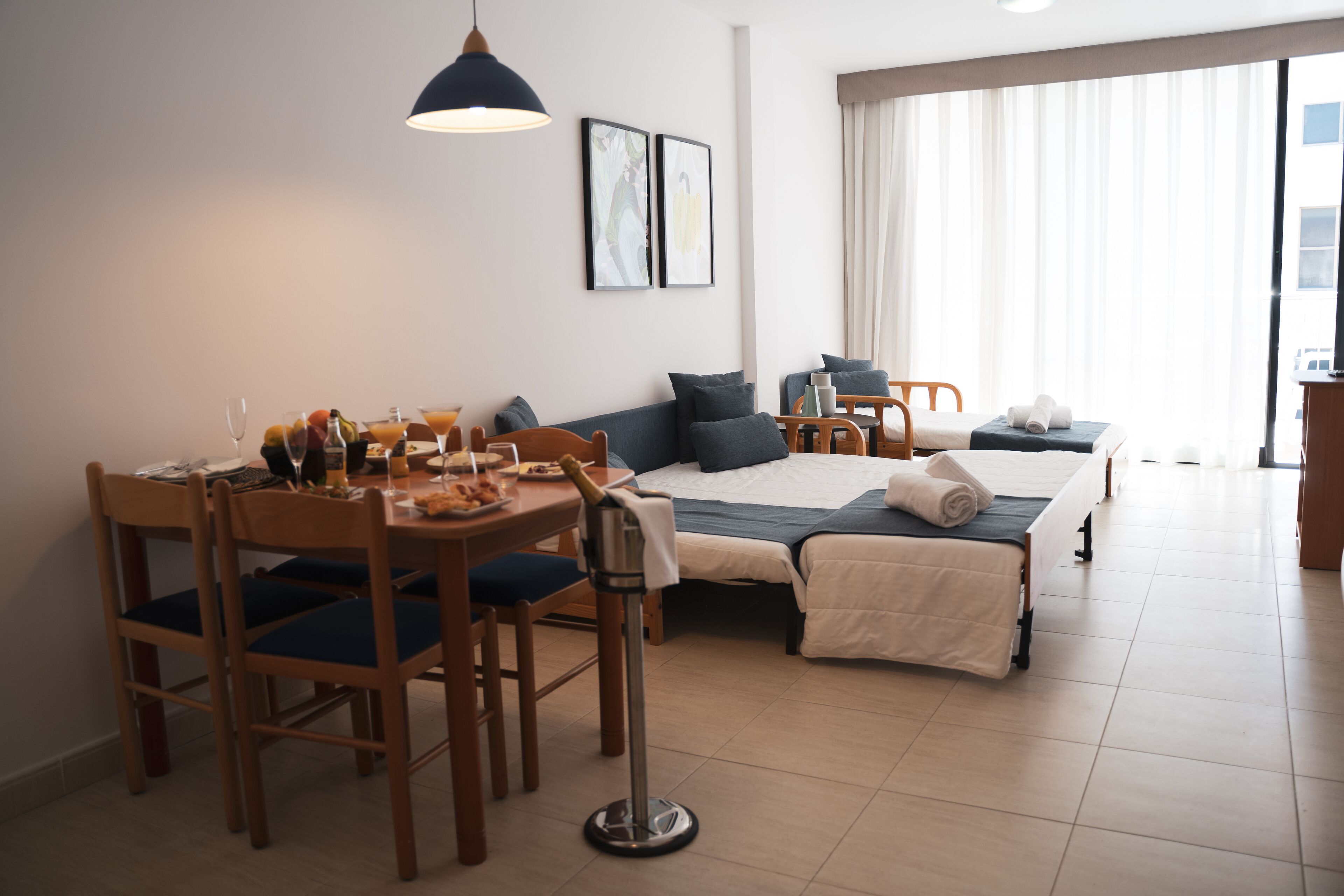 Een hotelkamer met een zithoek, een bed en een groot raam, plus een minibar.