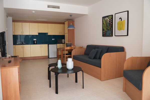 A modern living room with a sofa, coffee table, and a dining area with a table and chairs.