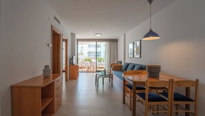 Un espacio habitable moderno y bien iluminado con una mesa de comedor de madera, sillas y un sofá. Hay un ventanal que proporciona luz natural y vistas al exterior.