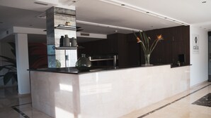 Una cocina moderna con encimera de mármol, armarios oscuros y un florero con flores.