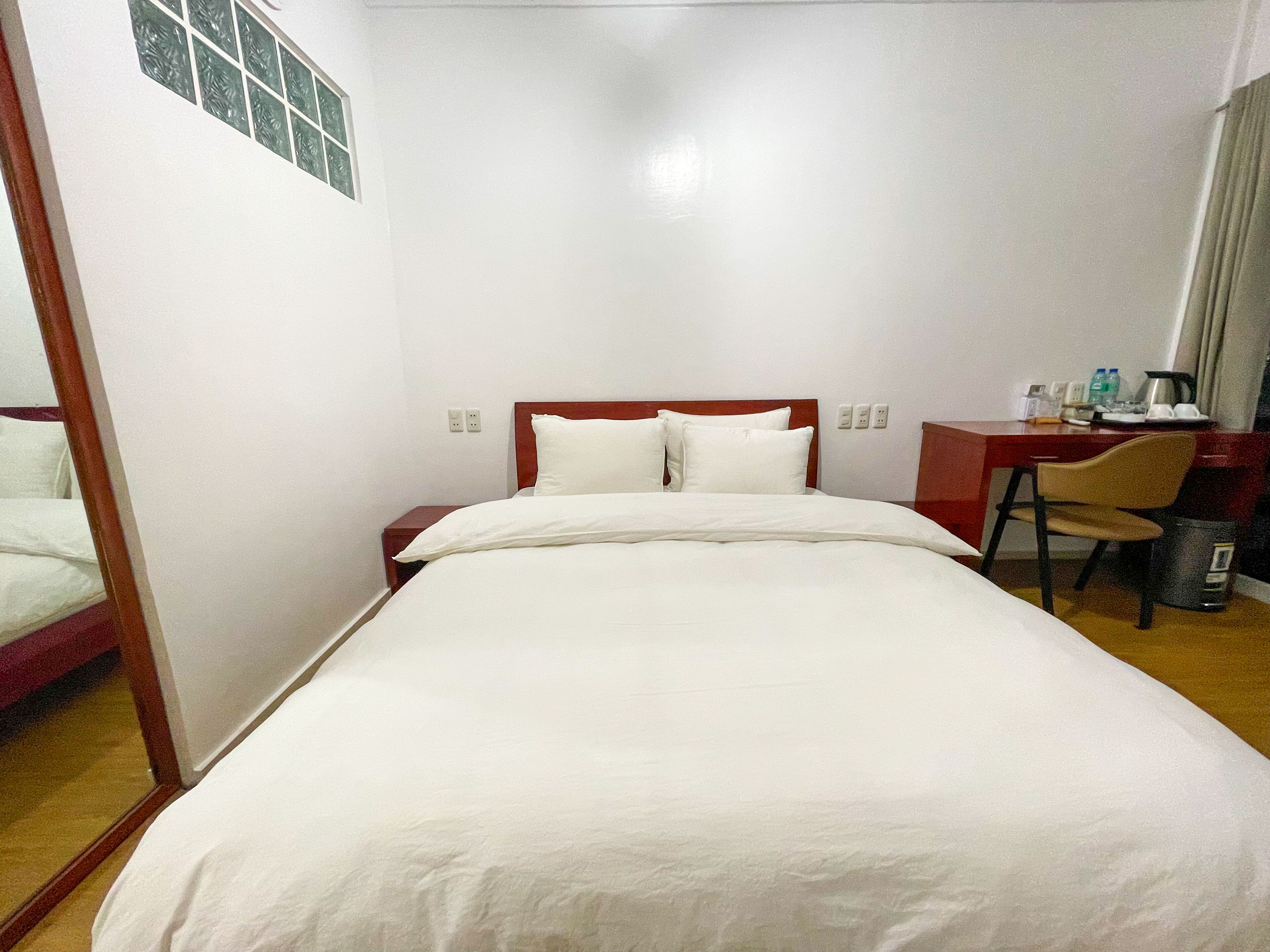Une chambre d’hôtel équipée d’un lit, d’un bureau, d’une chaise et d’une poubelle.