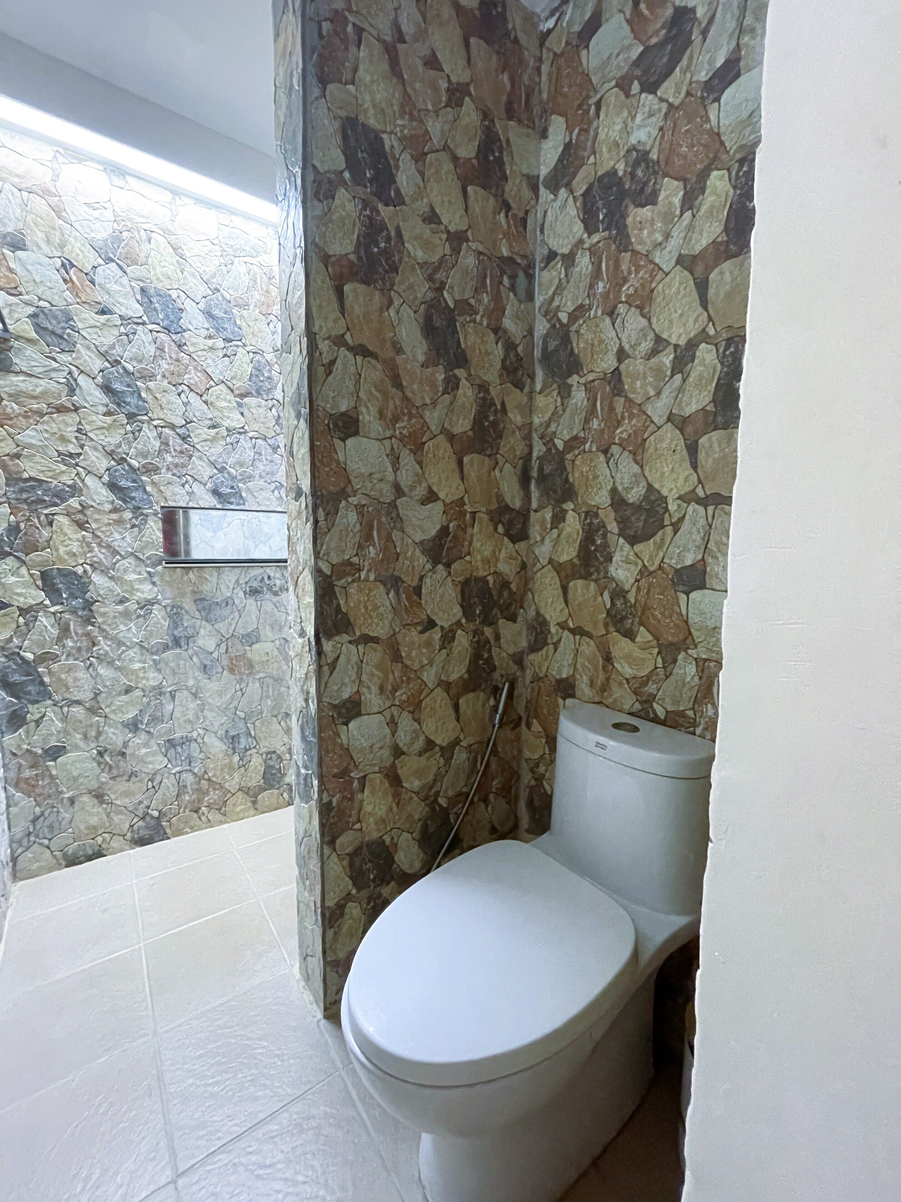 Een badkamer met een stenen muur, een toilet en een betegelde vloer.