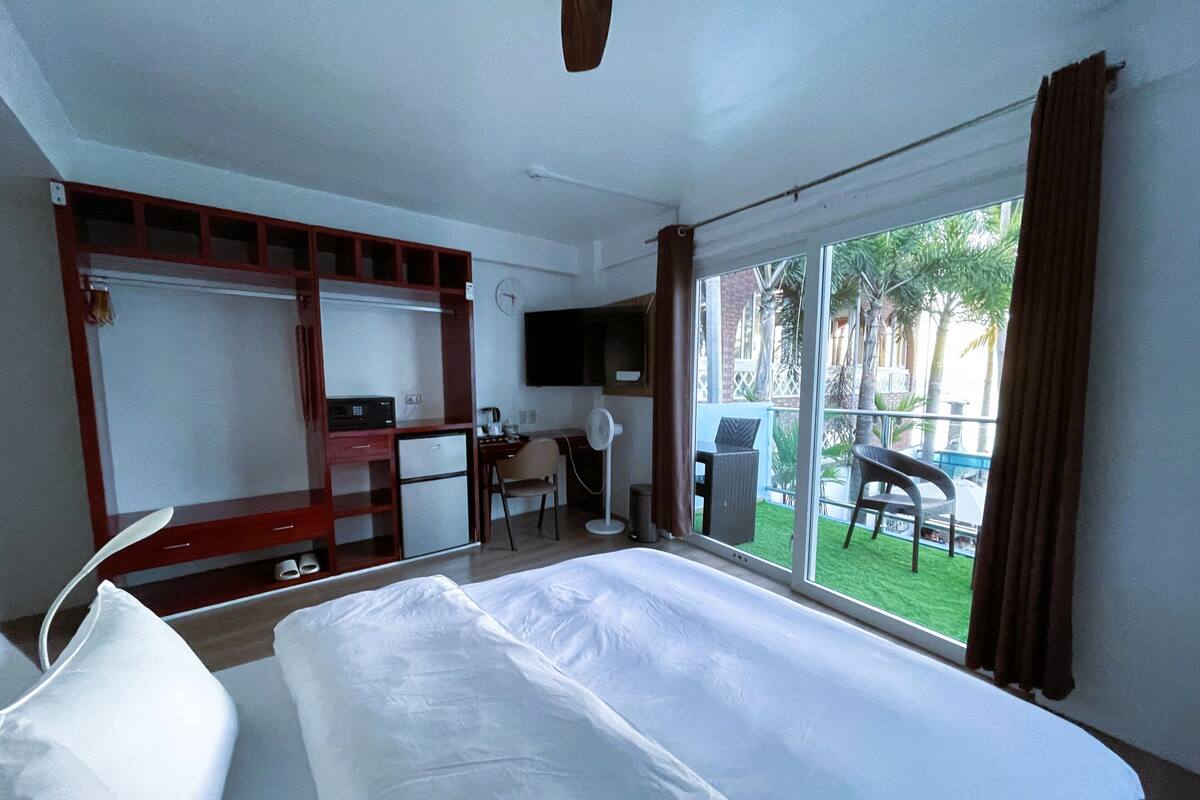 Habitación de hotel con cama, escritorio, silla y vistas al exterior.