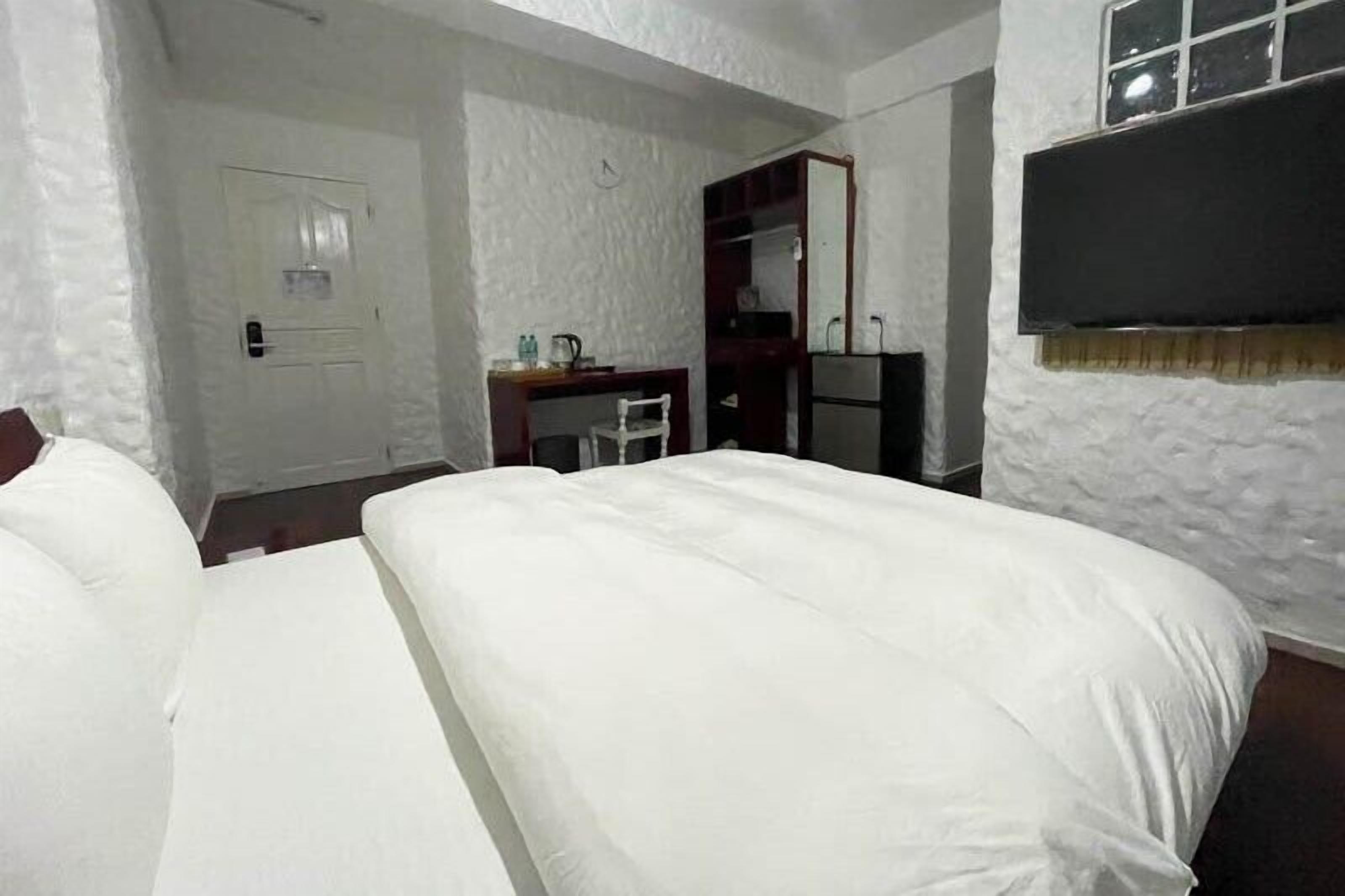 Een hotelkamer met een groot bed, een bureau, een stoel, een kledingkast en een televisie.
