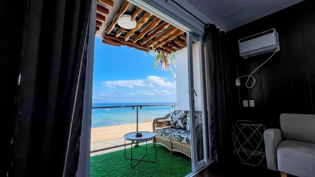 A room with a sliding glass door leading to a balcony with a view of the beach. - Montani Beach Resort Puerto Galera powered by Cocotel (Puerto Galera)