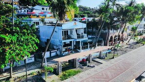 A resort building with a bar and restaurant on the ground floor, surrounded by palm trees and a paved walkway. - Montani Beach Resort Puerto Galera powered by Cocotel (Puerto Galera)