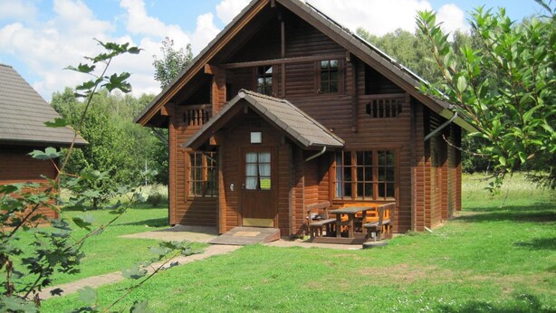 A wooden cabin with a front porch and a picnic table. - Ferienwohnpark Silbersee (Frielendorf)