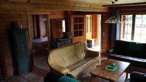 A cozy cabin interior with a wooden floor, a tan leather sofa, a wooden coffee table, and a black leather couch. - Ferienwohnpark Silbersee (Frielendorf)