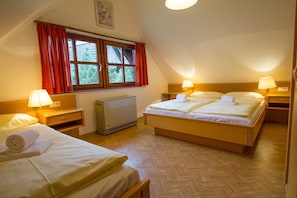 Ein Hotelzimmer mit zwei Betten, einem Heizkörper und einem Fenster mit roten Vorhängen.