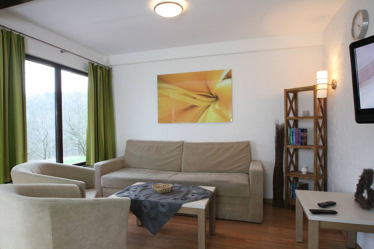 A living room with a beige sofa, a small table, and a bookshelf.