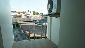 A balcony with a metal railing, a tiled floor, and a view of neighboring buildings. - Chouaprom Mansion (Nakhon Si Thammarat)