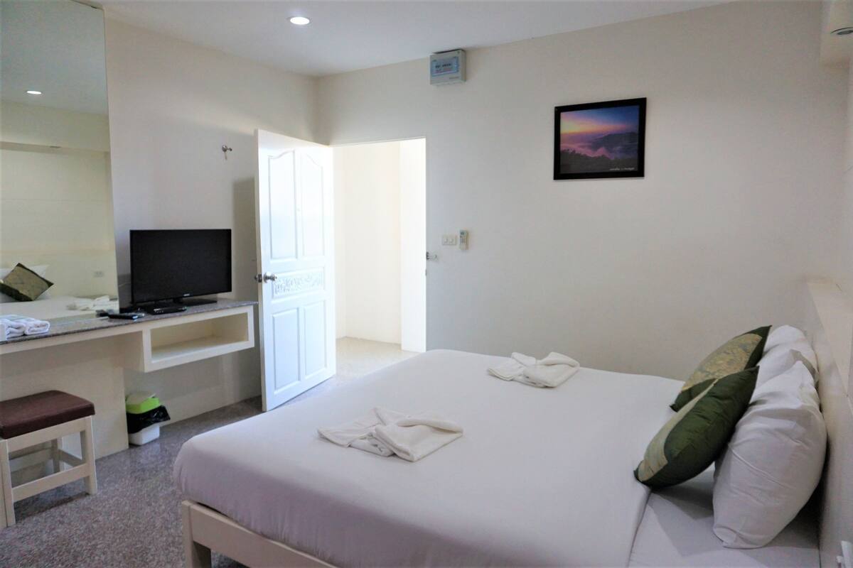 Une chambre d’hôtel comprenant un lit, un bureau avec une télévision et une porte donnant sur une autre pièce.