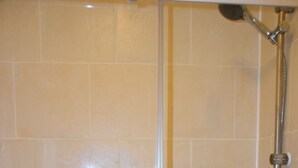 Una ducha con puerta de vidrio y cabezal de ducha de mano.