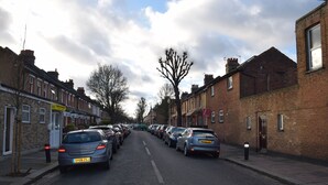 Una calle bordeada de coches aparcados y edificios residenciales.