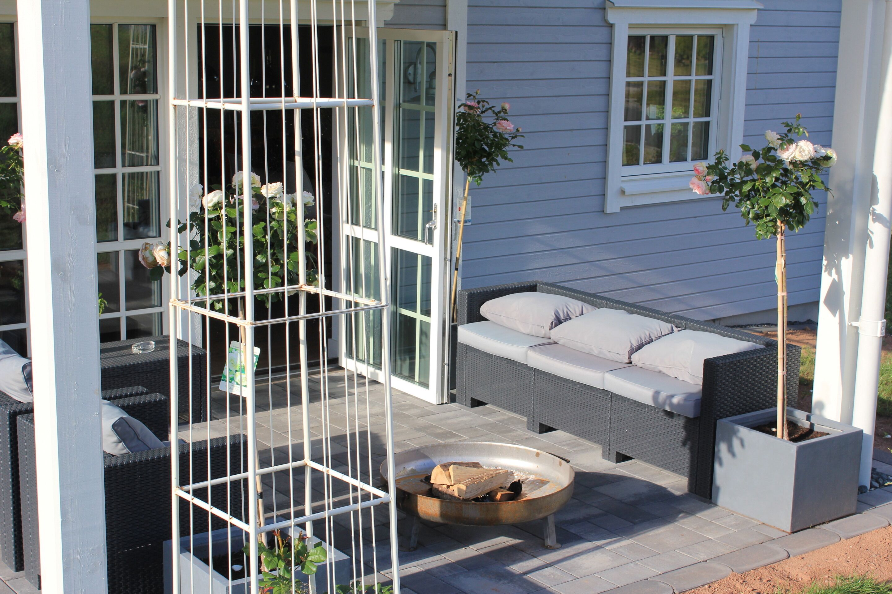 Eine Terrasse mit Gartenmöbeln, einer Feuerstelle und Kübelpflanzen.