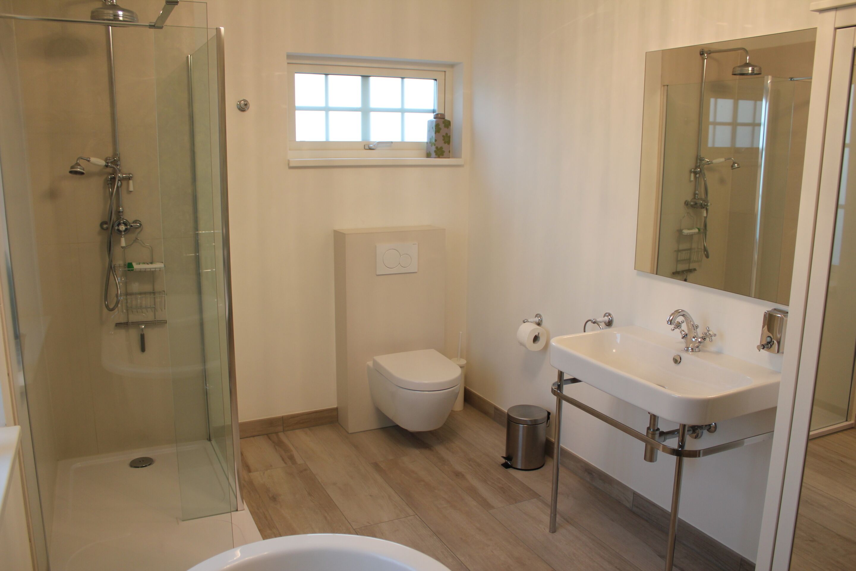 Une salle de bain moderne avec une douche à parois de verre, des toilettes, un lavabo et une fenêtre située au-dessus des toilettes.