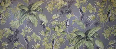 A wall with a repeating pattern of birds and foliage.