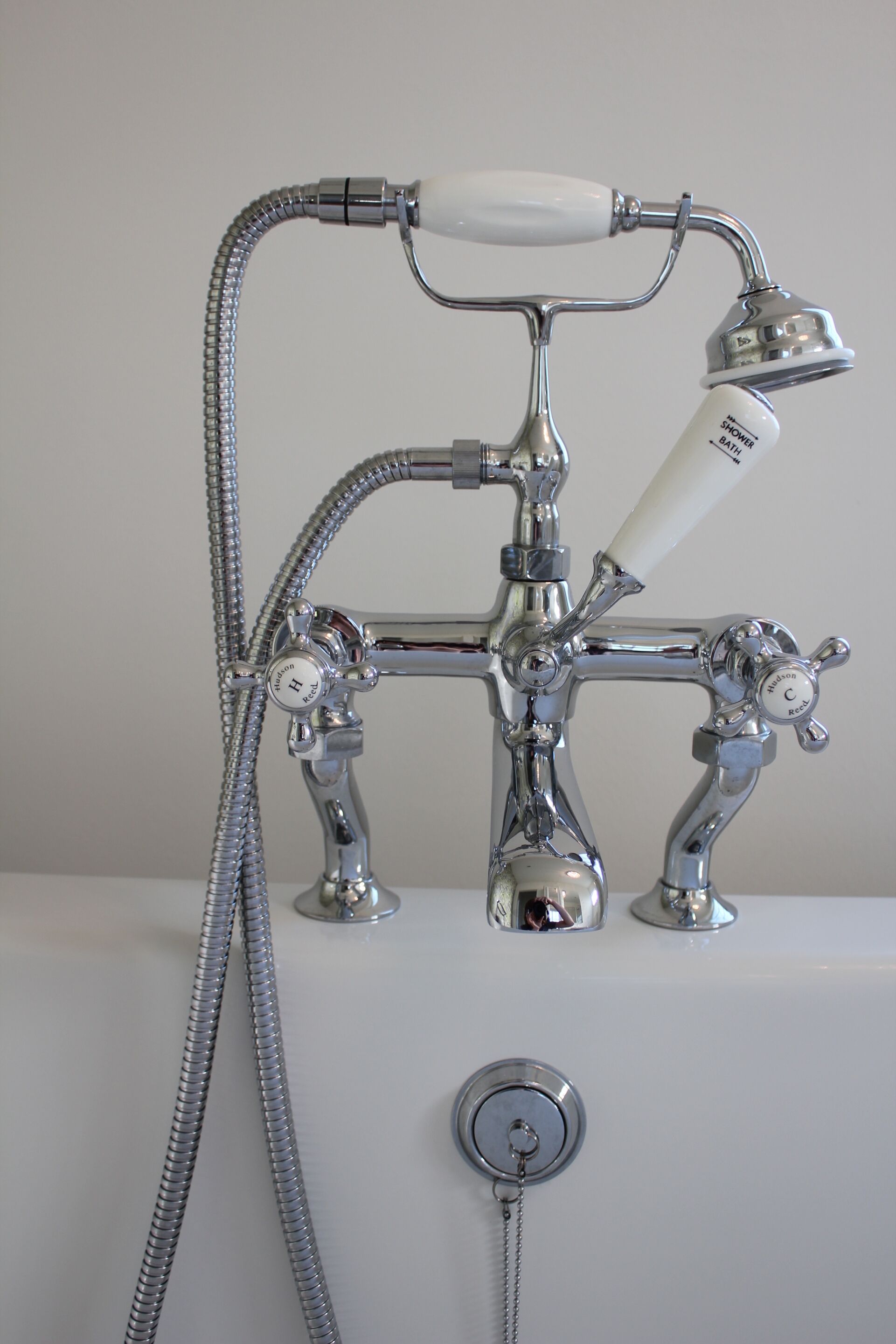 A bathroom with a classic chrome faucet, a handheld showerhead, and a separate shower control.