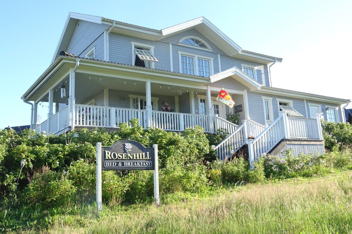A large, two-story building with a porch and a flag.