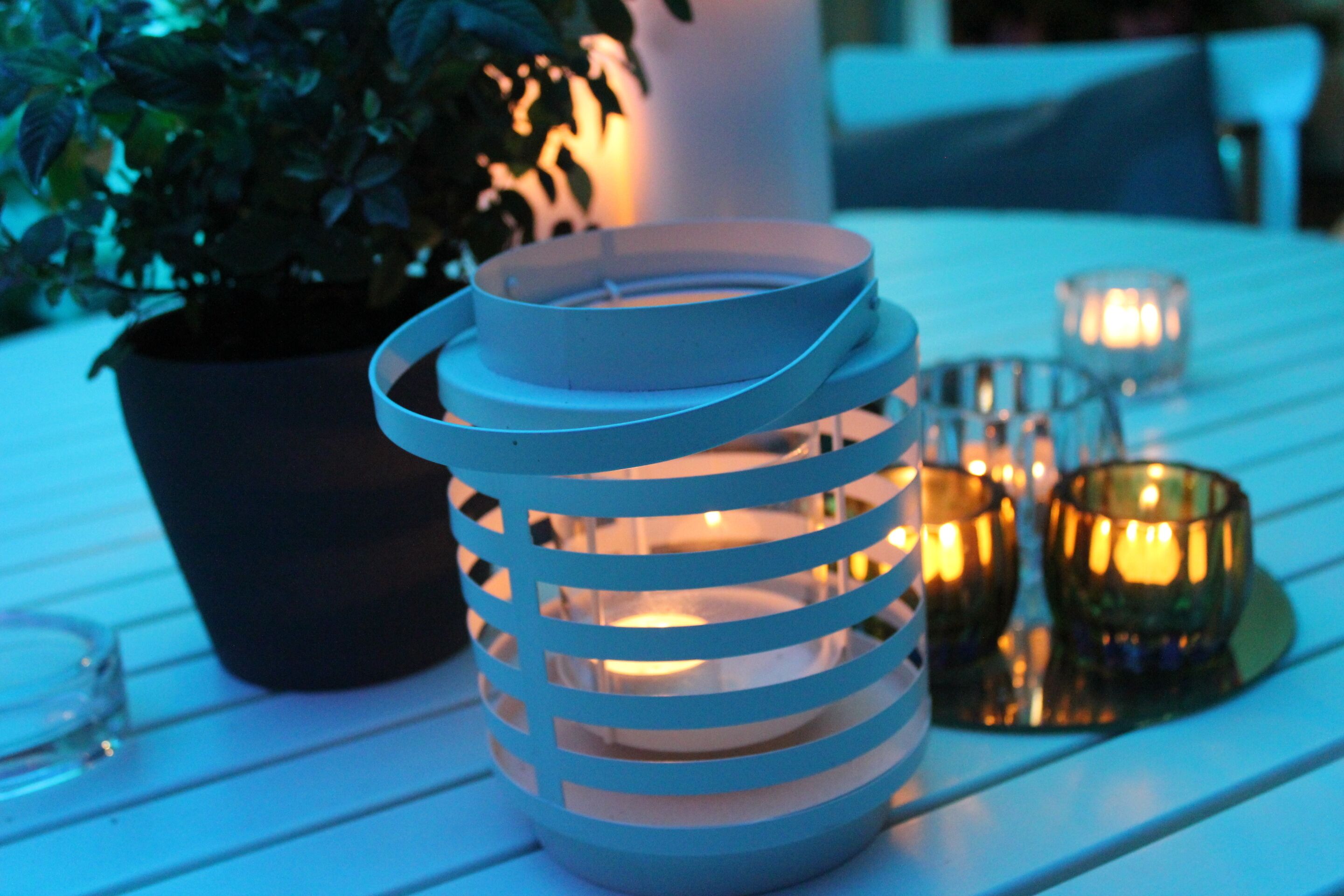 Una mesa con mantel blanco, una planta en maceta, un candelabro y velas.