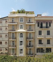 Un edificio de varios pisos con balcones, una entrada central y un techo plano.