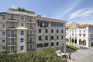 Un hotel de varios pisos con balcones, un patio central y cielo despejado.
