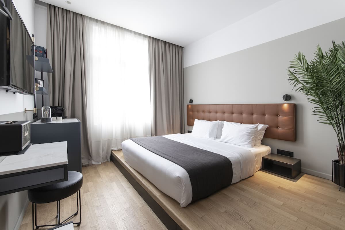 Ein modernes Hotelzimmer mit einem großen Bett, einem Schreibtisch und einer Pflanze.