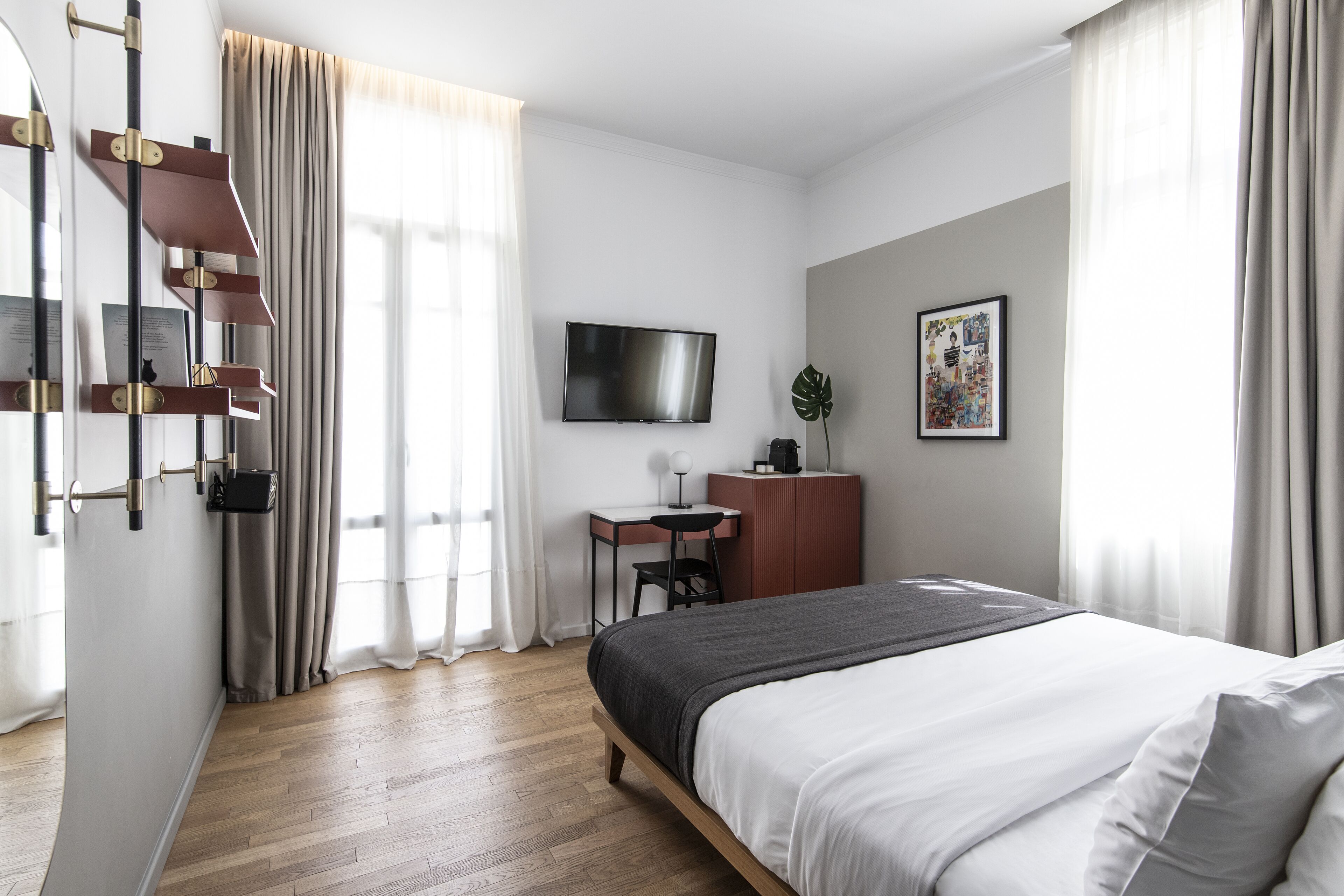 Een moderne hotelkamer met een groot bed, een bureau, een aan de muur bevestigde televisie en een raam met gordijnen.