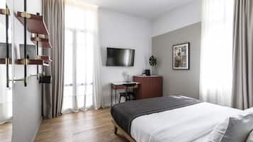 Een moderne hotelkamer met een groot bed, een bureau, een aan de muur bevestigde televisie en een raam met gordijnen.