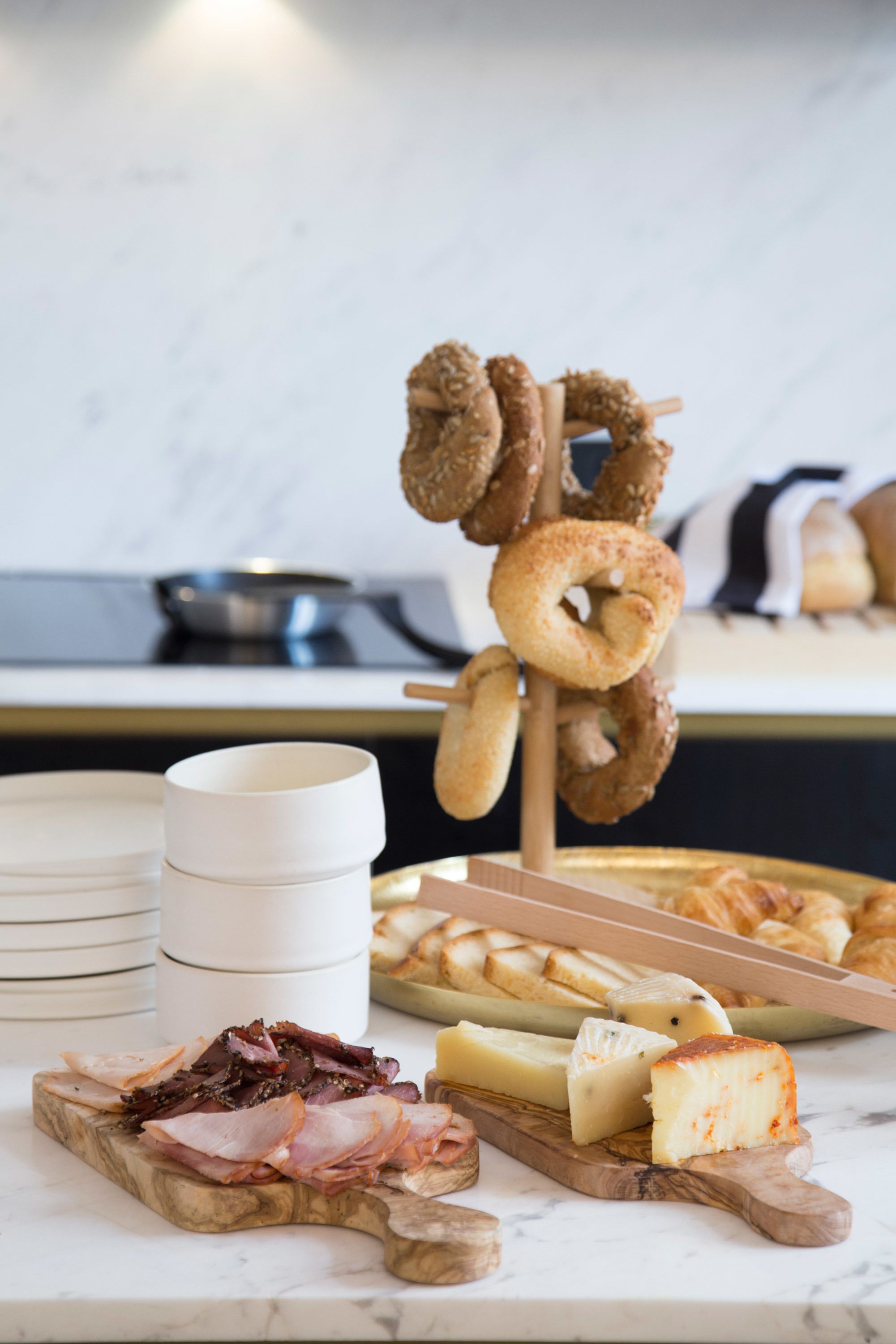 A breakfast buffet with various cheeses, meats, and pastries.