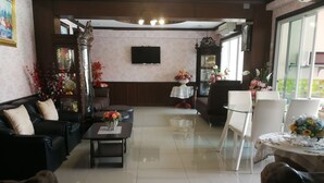 Ein geräumiges Wohnzimmer mit einer Couch, einem Couchtisch und Stühlen, einem Flachbildfernseher und dekorativen Blumenarrangements.