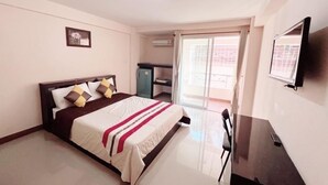 Ein Hotelzimmer mit Bett, Schreibtisch, Stuhl, Fernseher und einer Schiebetür zum Balkon.