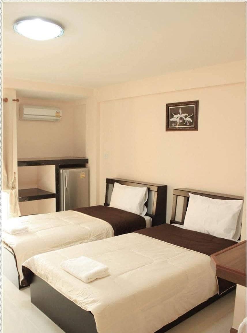 A hotel room with two beds, a kitchenette, and a ceiling light.