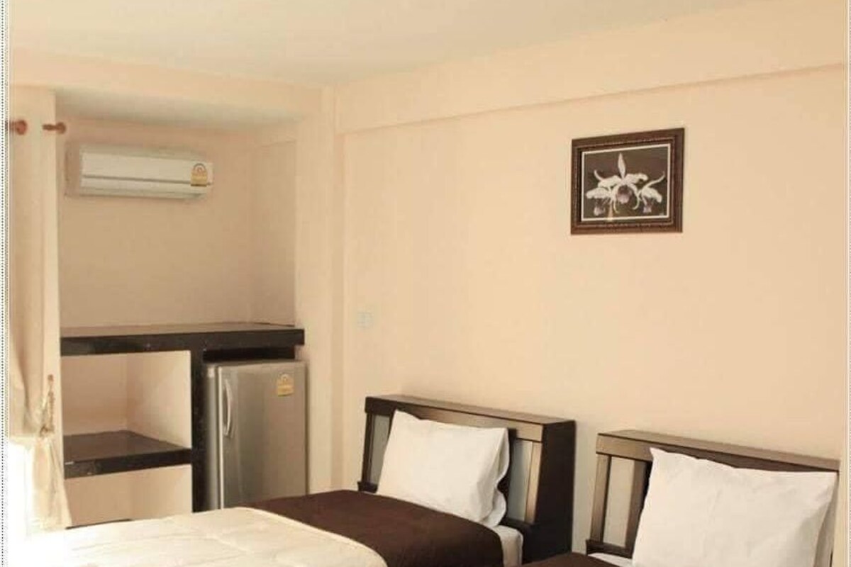 A hotel room with two beds, a kitchenette, and a ceiling light.