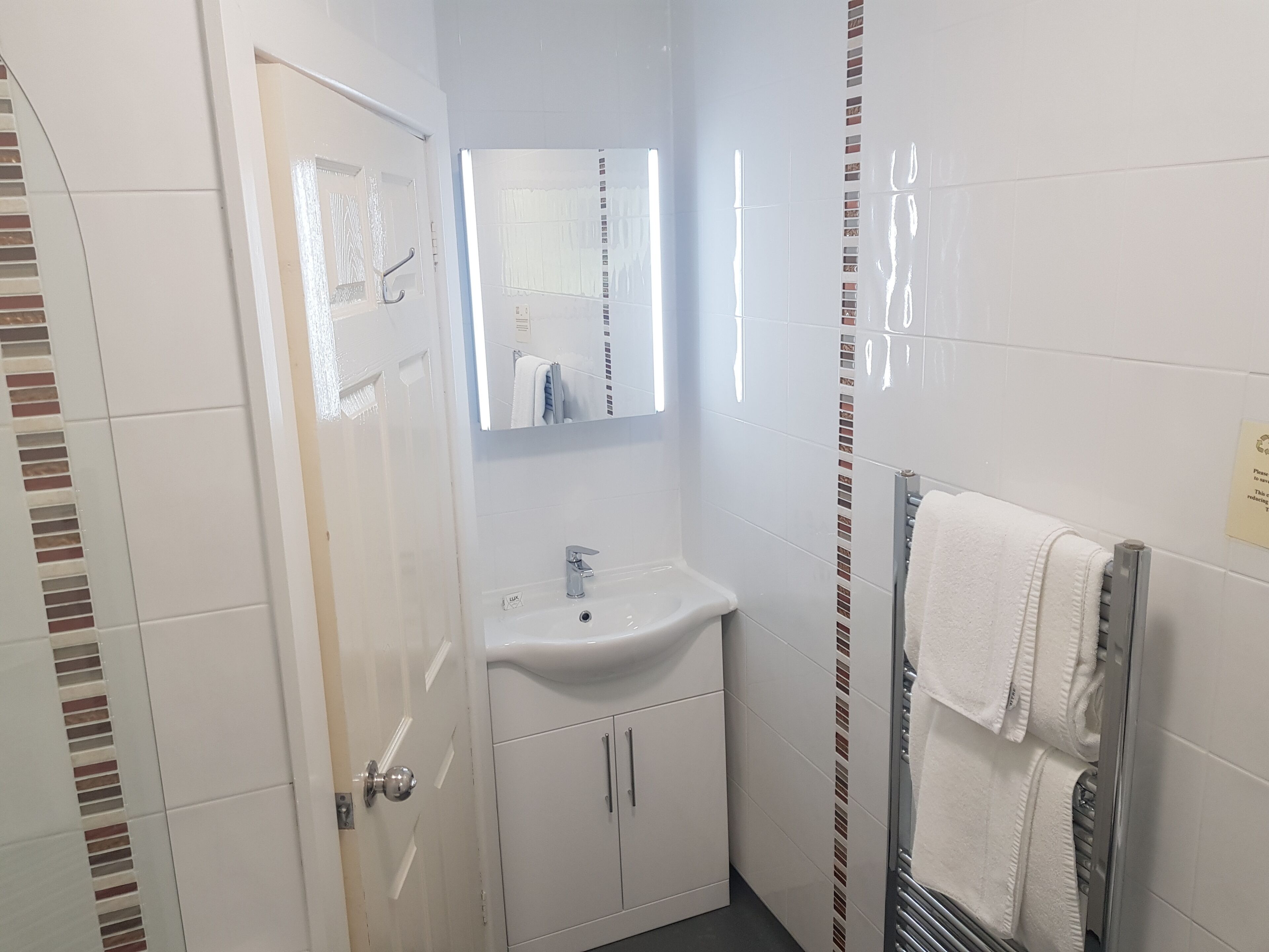 Een badkamer met een wit wastafel, een spiegel en een handdoekhouder.