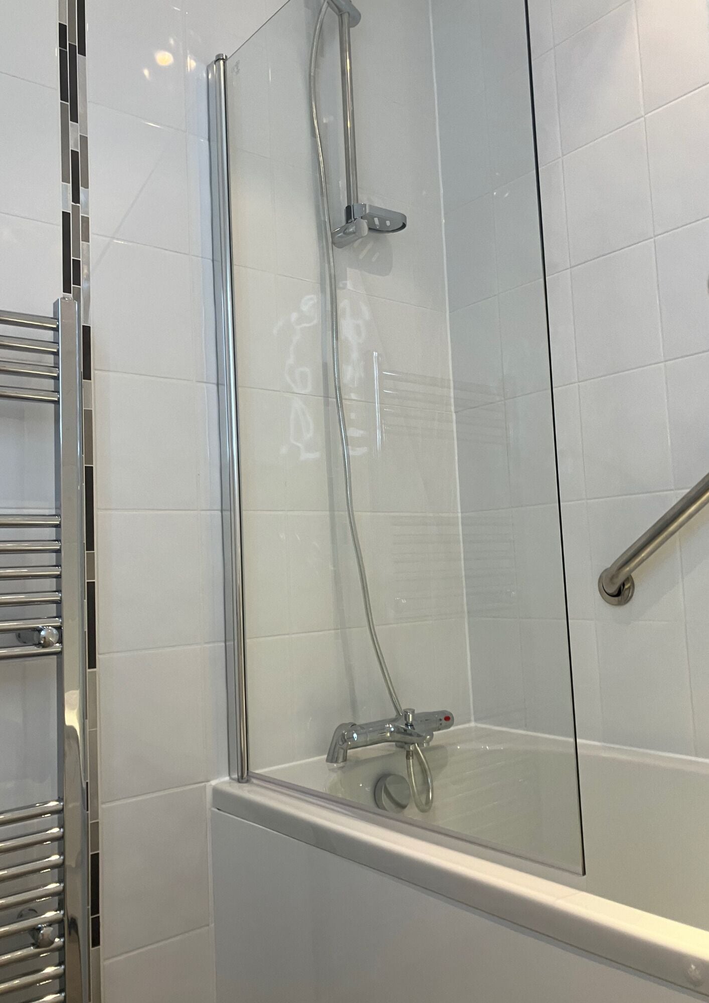 A glass-enclosed shower area with a chrome faucet and a handheld showerhead.