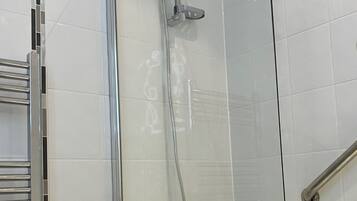 A glass-enclosed shower area with a chrome faucet and a handheld showerhead.