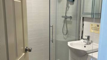 A modern bathroom with a glass-enclosed shower, a white sink, and a large mirror.