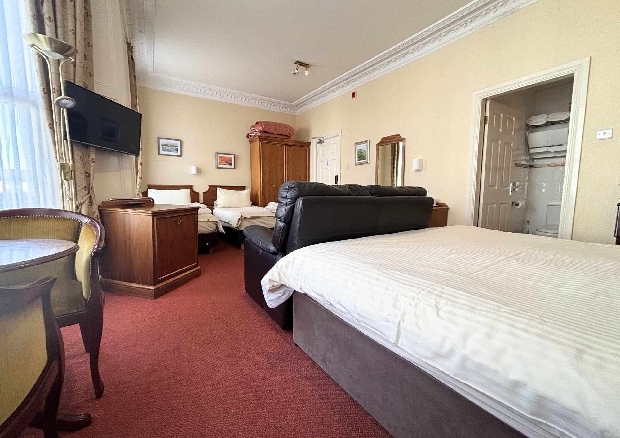 Une chambre d’hôtel équipée d’un lit, d’un bureau, d’une chaise, d’une télévision et d’une armoire.