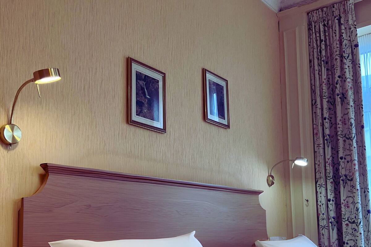 Une chambre d’hôtel avec un grand lit, deux lampes de chevet et un tableau encadré au mur.
